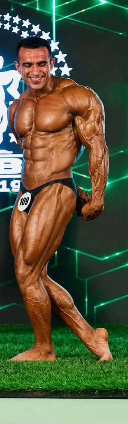 Coach Syed Fazal Elahi posing on stage at a physique championship